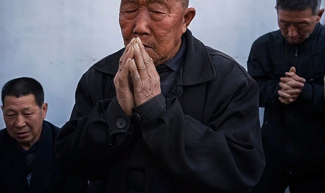Chineses orando em uma igreja subterrânea no quintal de uma casa. (Foto: Adam Dean/Panos)