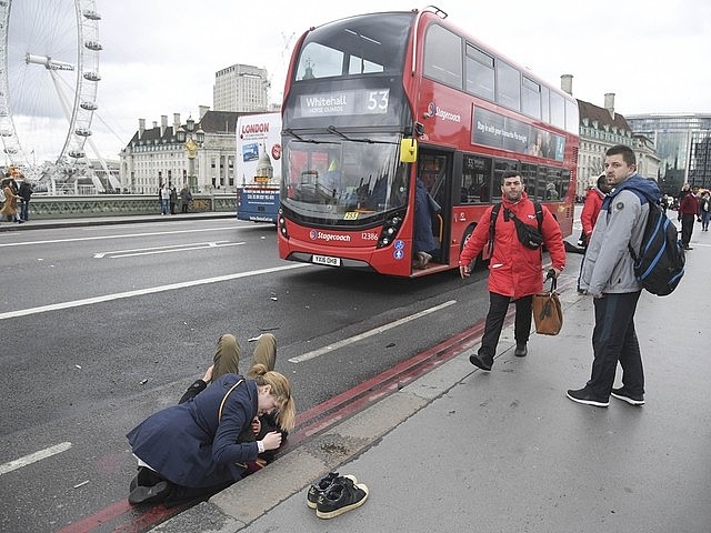 Mulher ajuda vítima ferida na ponte de Westminster, perto do edifício do Parlamento | Toby Melville/Reuters
